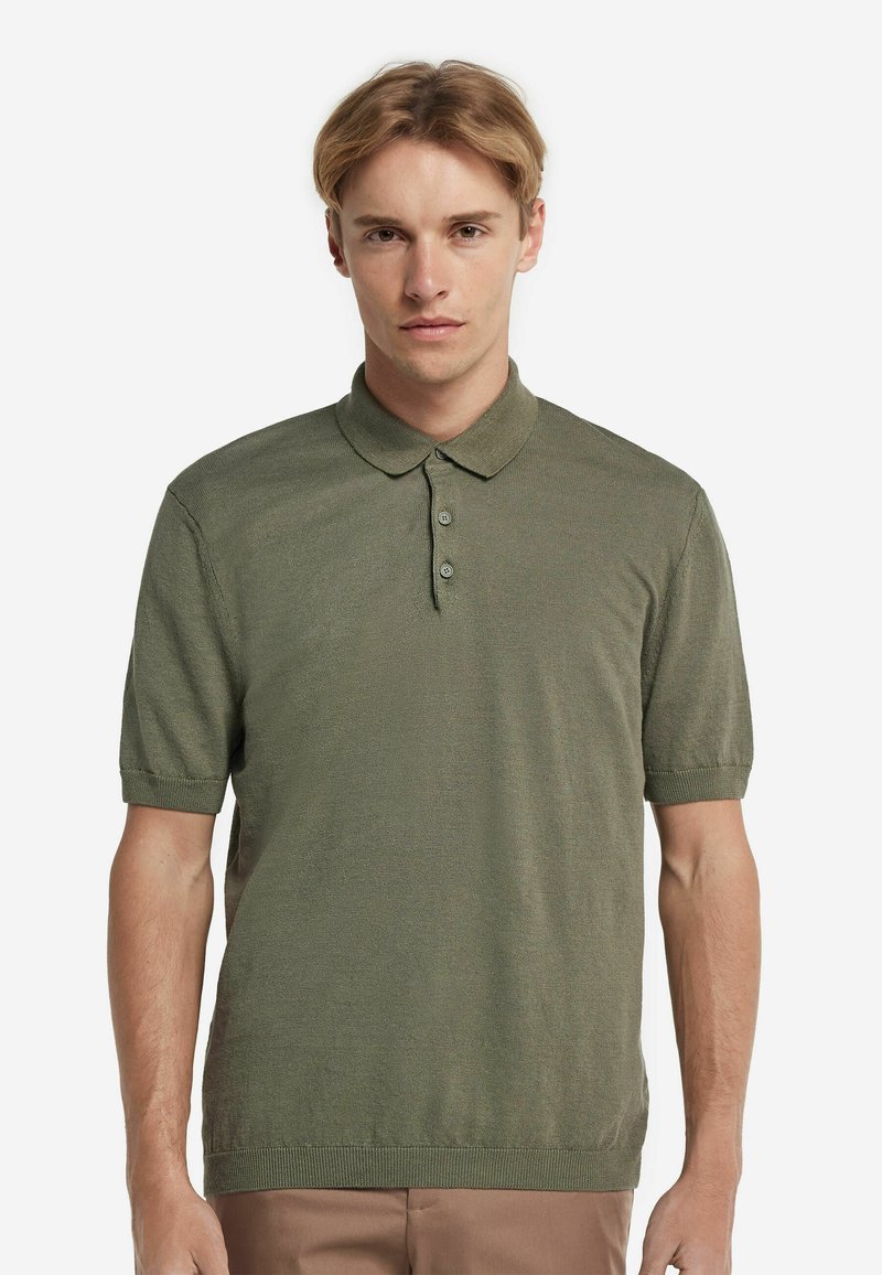 Olivgrön kortärmad polo skjorta i mjukt stickat tyg, med klassisk krage och plagg med tre knappar. Enkelt, strömlinjeformat design.