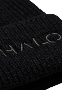 Svart stickad mössa med ribbat mönster och subtilt broderad logotyp. Materialet verkar mjukt och varmt, idealiskt för kallt väder.