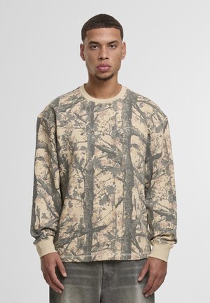 Beige langärmeliges Sweatshirt mit einer strukturierten Oberfläche und einem Tarnmuster, das Baumrinde ähnelt. Gerippte Bündchen und Halslinie, lockere Passform und dezente Markenkennzeichnung.
