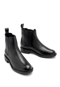 Bottes Chelsea en cuir noir avec panneaux latéraux élastiques, finition lisse, bout arrondi et petit talon carré. Accents texturés sur les côtés.