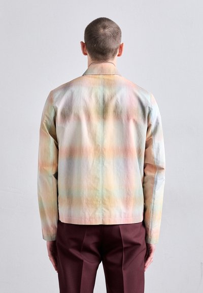 Giacca leggera dai colori pastello con una texture liscia, motivo a gradiente colorato e collo classico, abbinata a pantaloni bordeaux.