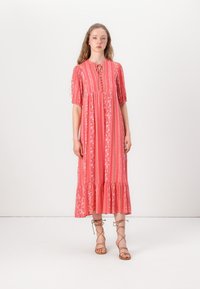 Coral maxi dress with puff sleeves, vertical floral and stripe patterns, button placket, and ruffled hem. Features soft, textured fabric.