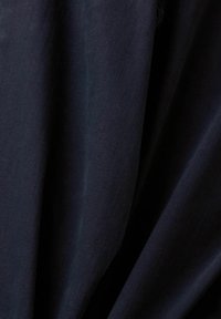 Tessuto blu navy dalla texture, con superficie liscia e leggermente lucida e pieghe drappeggiate. Leggero, adatto a diverse applicazioni tessili.