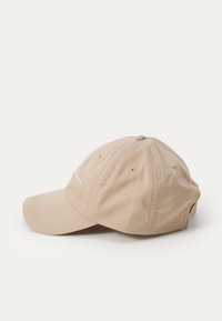 Beige baseball cap lavet af bomuld med en buet skygge, ventilationshuller og et broderet logo på forsiden. Justerbar rem bagpå.