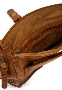 Sac fourre-tout en cuir tan avec un compartiment principal zippé, une poche zippée à l'intérieur et une texture lisse et doublée. Dispose d'une sangle robuste et d'une étiquette de marque.