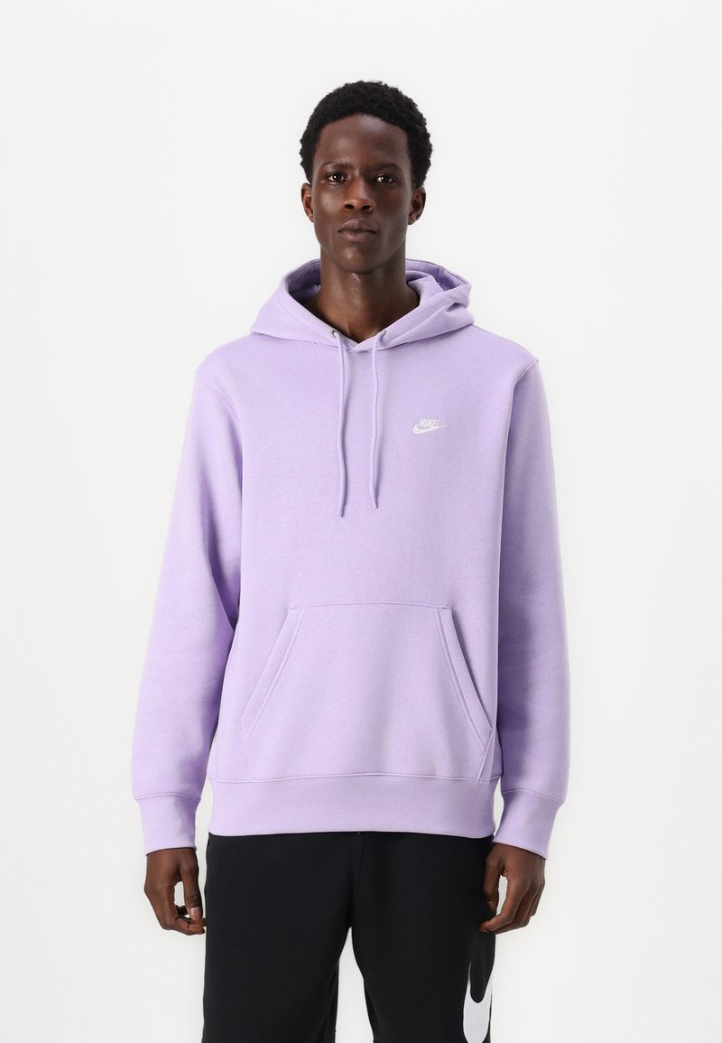 Felpa Nike di un delicato viola con tasca frontale, cappuccio regolabile e logo bianco sul petto. Abbinata a pantaloni neri con logo.