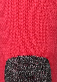 Tejido de punto rojo con una sección gris en la parte inferior. La textura es suave, mostrando una fina costura y un diseño de color sólido.