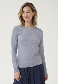 Hosszú ujjú csíkos ing, amely könnyű anyagból készült. Horizontális sötétkék és fehér csíkokkal, kerek nyakkivágással és testhezálló ujjakkal rendelkezik.