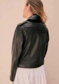 Černá kožená moto bunda s přiléhavým střihem, ramenními epauletami a zipovými manžetami. Hladká textura a minimalistický styl.