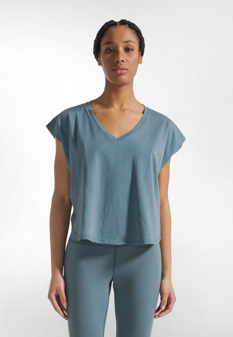Lyseblå, kortærmet v-hals crop top lavet af blødt stof, med en afslappet pasform og en let buet kant.