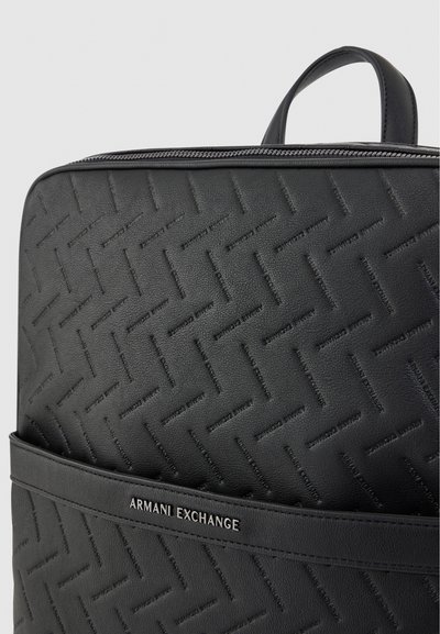 Крупен план на черна раница Armani Exchange с горна дръжка, закопчаване с цип, релефен геометричен мотив и преден джоб.