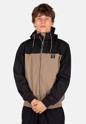 Wasserabweisende Jacke in Schwarz und Beige, mit einem Reißverschluss vorne, elastischen Bündchen, verstellbare Kapuze und einem Logopatch auf der Brust.