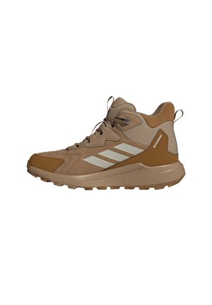 Brauner hoher Wanderschuh mit beigen Akzenten, Schnürdesign, robuster Sohle und "wasserdicht" Aufkleber an der Ferse.