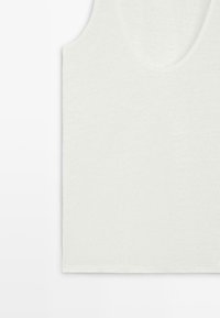 Débardeur blanc sans manches avec un col en U, présenté à plat sur un fond clair.