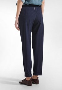 Granatowe, lekkie spodnie o luźnym kroju, z elastycznym pasem i dwoma tylnymi kieszeniami. Spodnie mają mankiety u dołu nogawek i są zestawione z bordowymi butami.