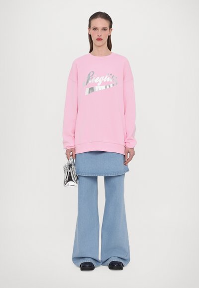 Felpa rosa con testo metallico, jeans blu a campana e una borsa argento. Tessuto morbido con vestibilità comoda e gambe dei pantaloni larghe.
