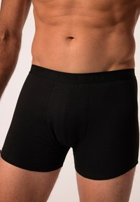 Boxer shorts neri realizzati in tessuto morbido, con una fascia elastica liscia e un marchio testurizzato in un colore abbinato.