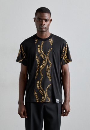 T-shirt noir avec un motif de chaîne dorée et le texte "Versace Jeans Couture", présentant un col rond et des manches courtes, fabriqué en tissu doux.