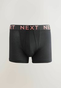 Bañadores negros ajustados con un diseño entallado y un logo rosa de "NEXT" en la cintura. Tejido suave con una textura lisa.