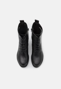 Bottes dcheville en cuir noir  texture lisse, avec des lacets  l'avant, des fermetures  glissire latrales et un design  bout arrondi.