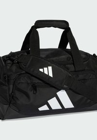 Bolsa de viaje negra hecha de tela duradera, con correas verticales y horizontales, múltiples bolsillos con cremallera y distintivos detalles de logotipo en blanco.
