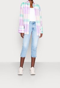 Kevyt, pastellinvärinen ruudullinen nappipaita pitkillä hihoilla, yhdistettynä vaaleansinisiin cropattuisiin farkkuihin ja beigeihin lenkkareihin. Pehmeä puuvillakangas.