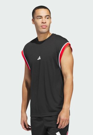Man wearing black sleeveless athletic shirt with red and white trim and matching black shorts, looking to the side against a light background.