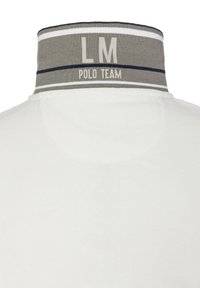 Bílá polokošile se šedým límečkem s tmavě modrými pruhy. Na límečku je vytištěno "LM" a "POLO TEAM" světle barvou.