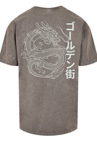 Grey oversized T-shirt featuring a large white dragon graphic and Japanese text on the back. Made of soft, textured fabric with subtle distressing.