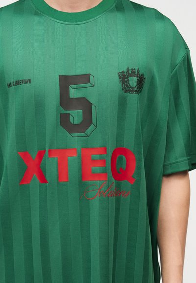 Πράσινη αθλητική φανέλα με μαύρο αριθμό 5, μαύρο σήμα, κείμενο "HAN KJØBENHAVN" και μεγάλο κόκκινο λογότυπο "XTEQ Solutions" στο μπροστινό μέρος.