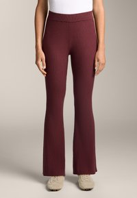 Leggings a costine e svasati di un profondo bordeaux, realizzati in un tessuto morbido con vita alta. Presentano un design testurizzato.