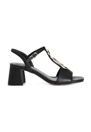 Sandal in pelle nera con tacco a blocco, caratterizzata da punta aperta, cinturini sottili e un accento decorativo in oro.