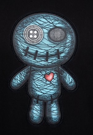 Blaues Cartoon-Figur mit gestickten Details, einem Knopf-Auge und einem roten Herzen auf der Brust, vor einem schwarzen Hintergrund.