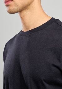 Felpa girocollo blu navy scuro con una texture liscia e colletto a costine, con dettagli cuciti sulle cuciture delle spalle.