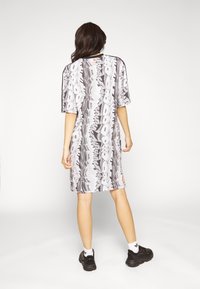 Vestido camiseta oversize en gris monocromo con patrones abstractos en blanco y negro, mangas cortas y corte recto. Calzado y calcetines negros.