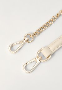 Gold metal chain strap with two clasps, attached to a cream leather section. Smooth texture with subtle stitching details.