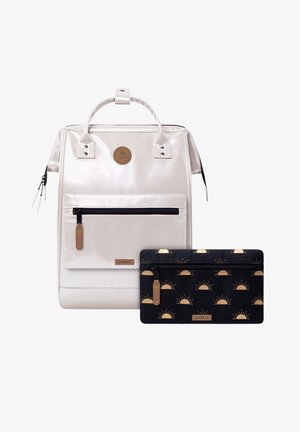 Sac à dos brillant de couleur blanc cassé avec poche zippée avant et poignée supérieure, accompagné d'une pochette noire zippée ornée de motifs de soleils couleur beige.