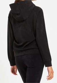 Sudadera con capucha negra de tejido suave y texturizado. Presenta un corte relajado, bolsillo canguro y puños y dobladillo de canalé.