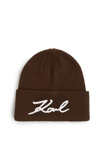 Brun strikket lue med brettet skjerf som har hvit brodert kursiv tekst som leser "Karl" på fronten.