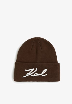 Pruneeritud kootud beanie, millel on volditud äär, ja esipooltel on valge tikandiga kursiivtekst "Karl".