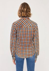 Camicia a quadri in tonalità arancione, blu e marrone; chiusura con bottoni sul davanti, maniche lunghe e colletto appuntito; tessuto morbido con una finitura texture.