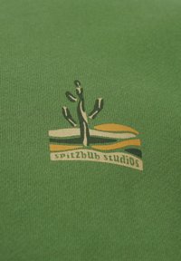 Grüner Stoff mit strukturiertem Strick, versehen mit einem Druckdesign eines Kaktus und dem Text "spitzbub studios" in cremefarbenen und gelben Akzenten.
