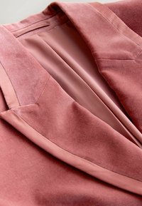Rose pink blazer made of soft velvet, featuring a smooth inner lining, tailored collar, and neatly stitched edges.