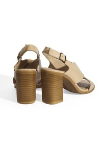 Beige Absatzsandalen mit glänzender Oberfläche, offener Zehenpartie, Slingback-Design, gesichert durch eine verstellbare Schnalle, mit strukturierten, geriffelten Blockabsätzen.