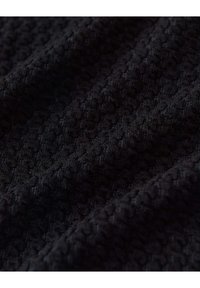 Tissu noir texturé avec un motif légèrement en relief. Le matériau semble doux et tricoté, avec une structure étroitement tissée.