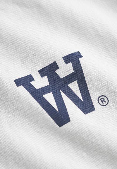 Tessuto bianco con una grande lettera "W" di colore blu navy e un simbolo di marchio registrato. Il logo ha un aspetto testurizzato.