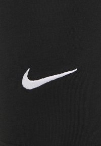 Svart atletisk tyg med en texturerad väv; har en framträdande vit broderad Nike swoosh-logotyp.