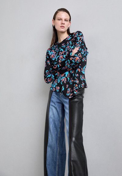 Black blouse with colorful swirling patterns, paired with high-waisted jeans featuring a leather panel on one side. Smooth texture, relaxed fit.