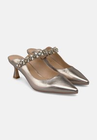 Zapatos de slingback de punta metálica dorada con tacón bajo, que cuentan con una correa decorativa de cristales a través del mediopié. Textura suave.