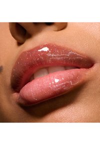Närbild av fylliga läppar med en glansig, genomskinlig yta, prydda med fina glitternanopartiklar. Färgen är en mjuk rosa med en jämn textur.